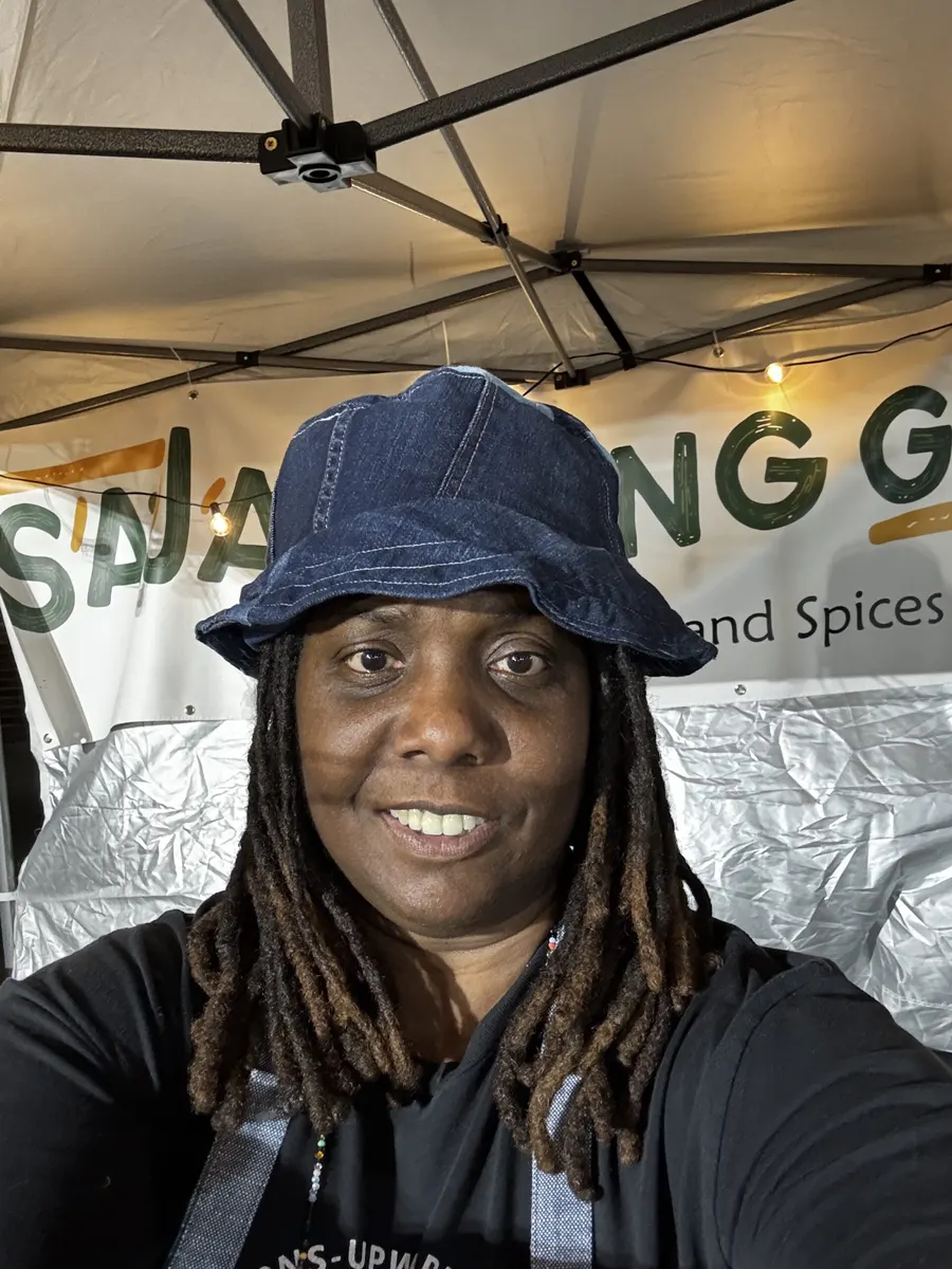 Trelisa, founder of Saja Living Garden, smiling in a blue bucket hat at her market booth